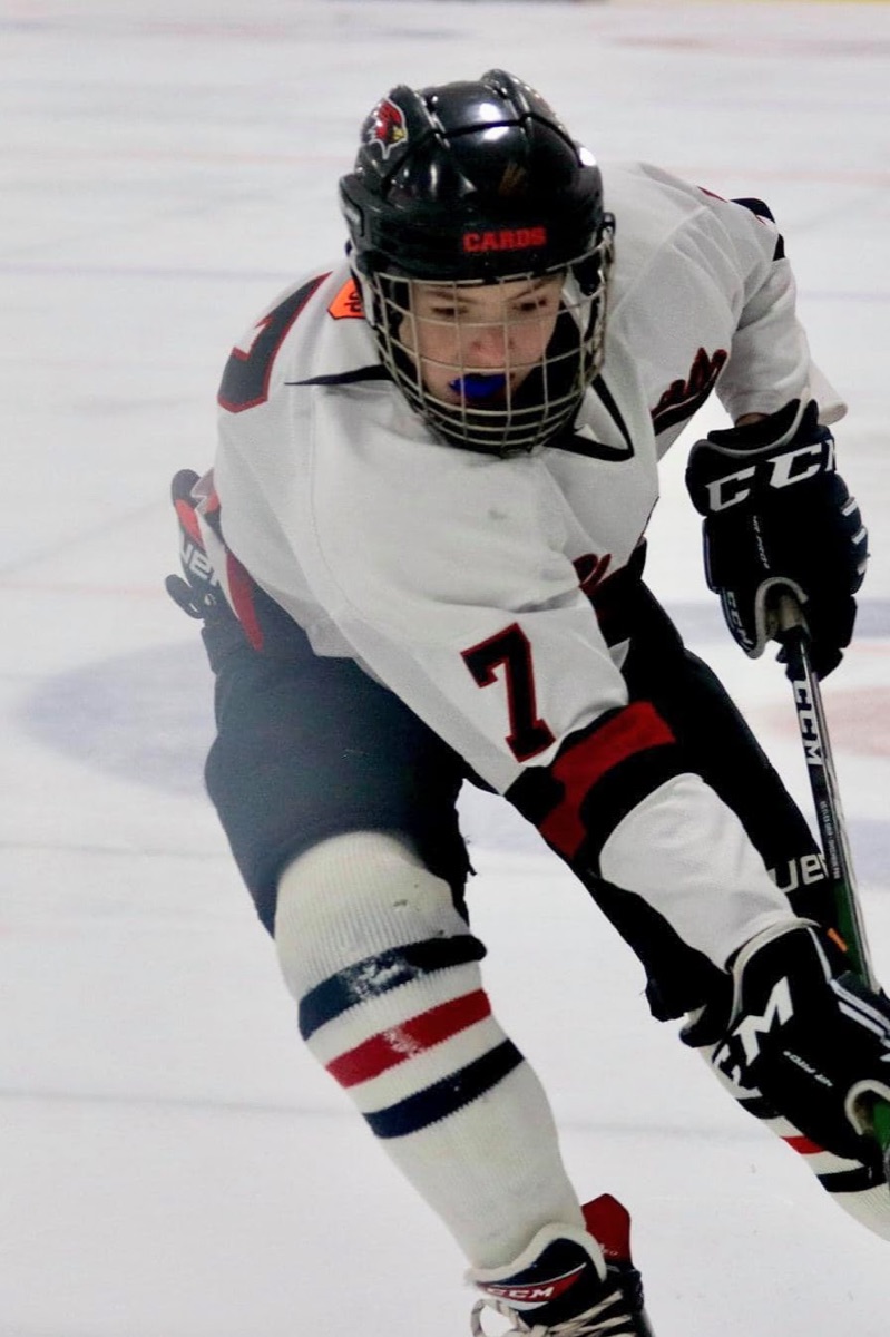 Jackson skating with the puck in his Alexandria Cardinals jersey